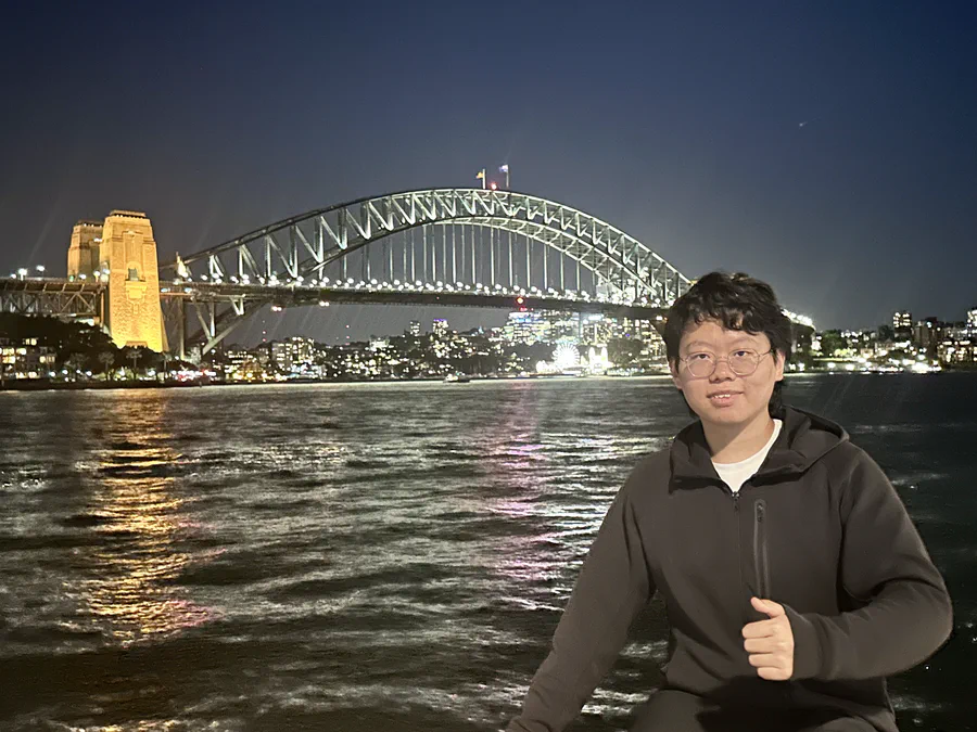 Yixiong Gao standing in front of Sydney Harbour Bridge at night